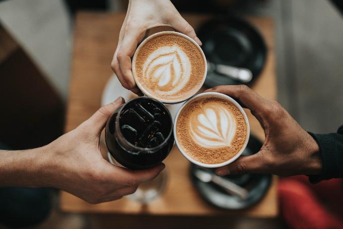 Tres personas sosteniendo vasos de bebidas de café